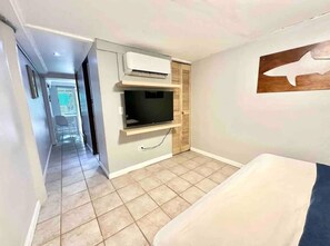 Een kamer met een bed, een televisie en een wandairconditioner.