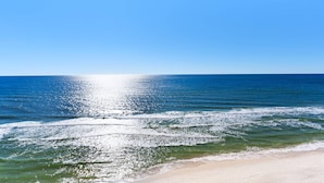 Une plage avec une eau d’un bleu limpide et un rivage sablonneux.