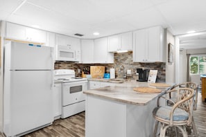A modern kitchen with white cabinets, a granite countertop, and a built-in stove. - Sugar Beach C-8 (Panama City Beach)