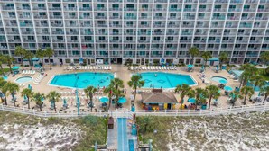 A hotel with multiple balconies, a central swimming pool, and a beach area with sun loungers. - Summit Beach Resort 1429 (Panama City Beach)