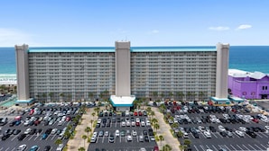 A large hotel with a parking lot in front, a beach view, and a clear sky. - Summit Beach Resort 1429 (Panama City Beach)