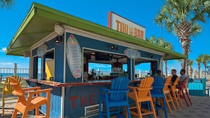 A tiki bar with outdoor seating and a menu board. - Summit Beach Resort 1429 (Panama City Beach)