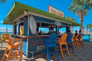 A tiki bar with outdoor seating and a menu board. - Summit Beach Resort 1429 (Panama City Beach)