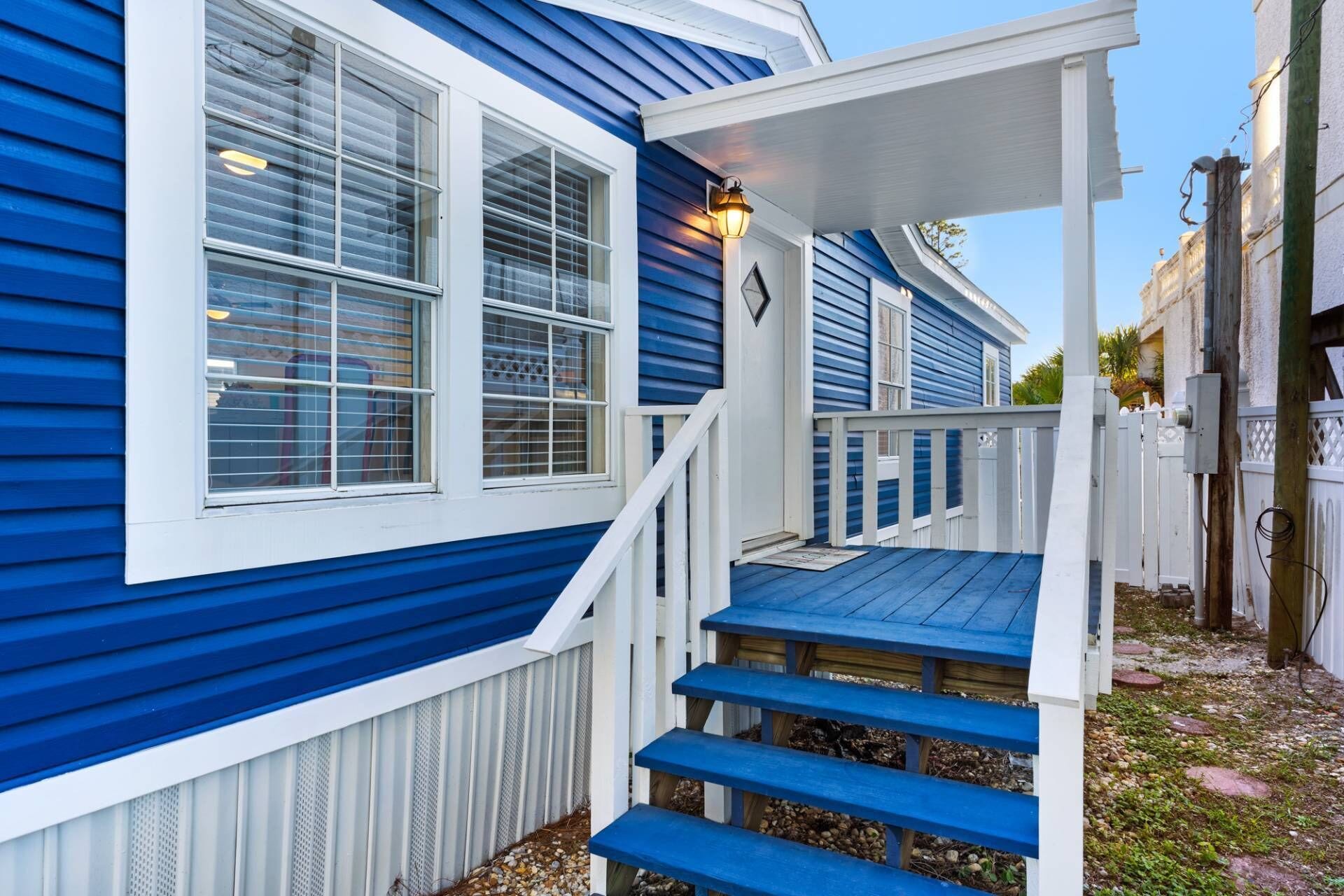 A blue house with white trim, a front porch with steps, and a light fixture on the porch.