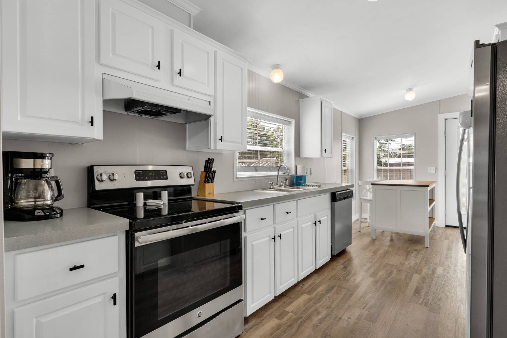 A modern kitchen with white cabinetry, a stainless steel stove, and a built-in oven.