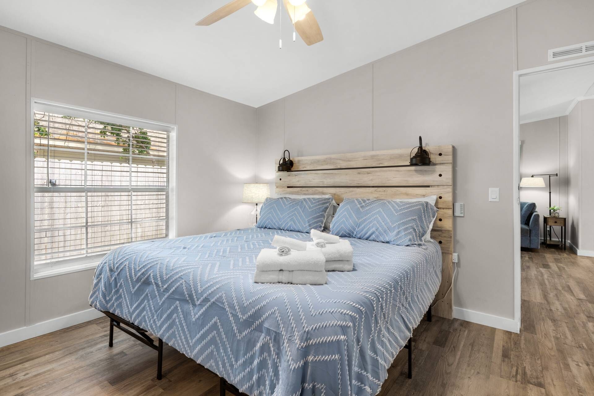 Une chambre à coucher avec un lit, une fenêtre, un ventilateur de plafond et une table de chevet.