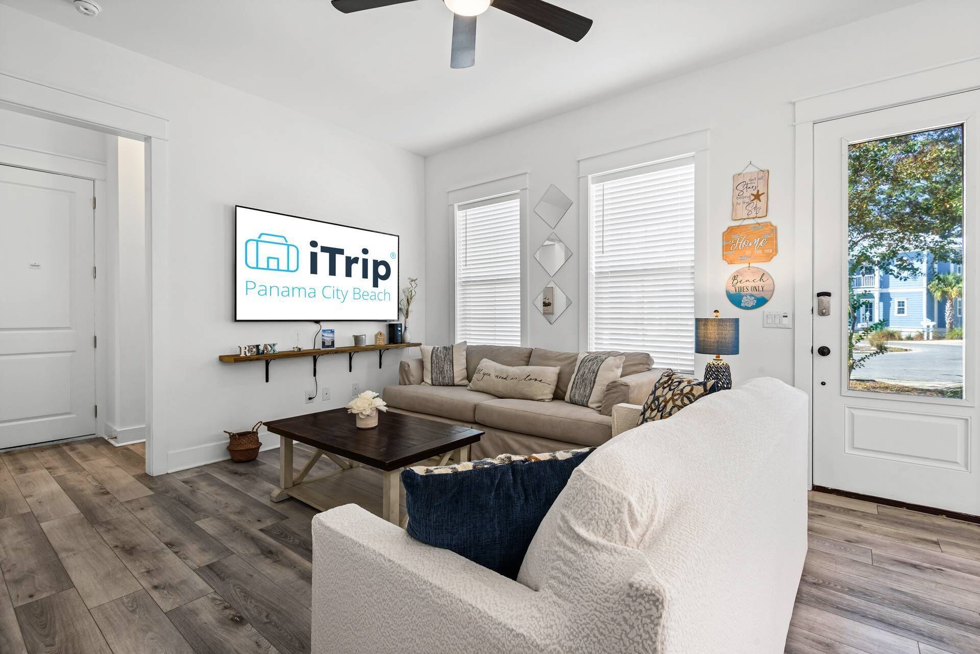 Una sala de estar con un sofá, una mesa de centro y un televisor que muestra 'iTrip Panama City Beach'.