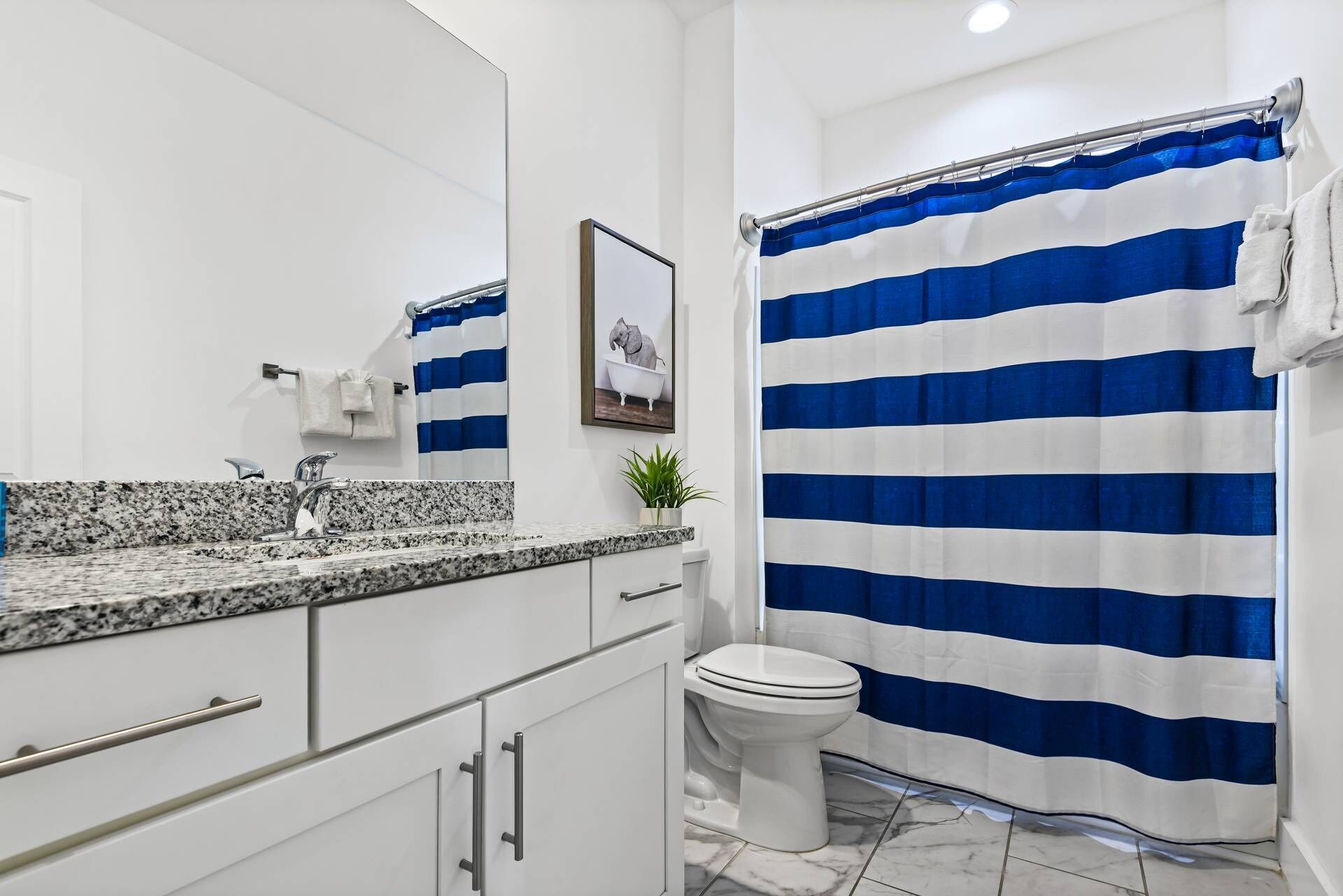 A bathroom with a white sink, a white toilet, and a blue and white striped shower curtain.