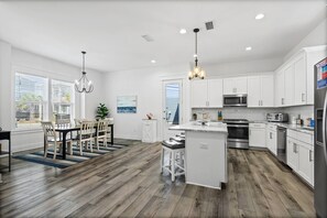 A modern kitchen with white cabinets, stainless steel appliances, and a wooden floor. - Blue Lagoon (Panama City Beach)