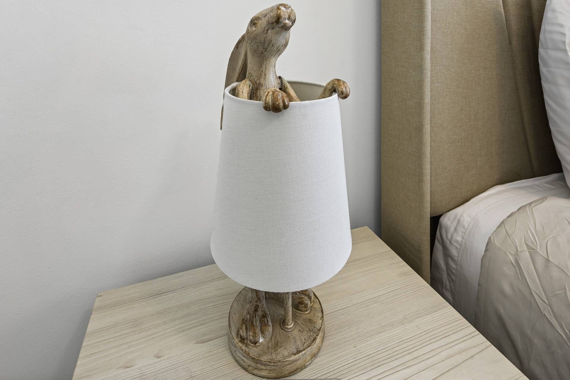 A lamp with a wooden base and a white lampshade on a wooden nightstand.