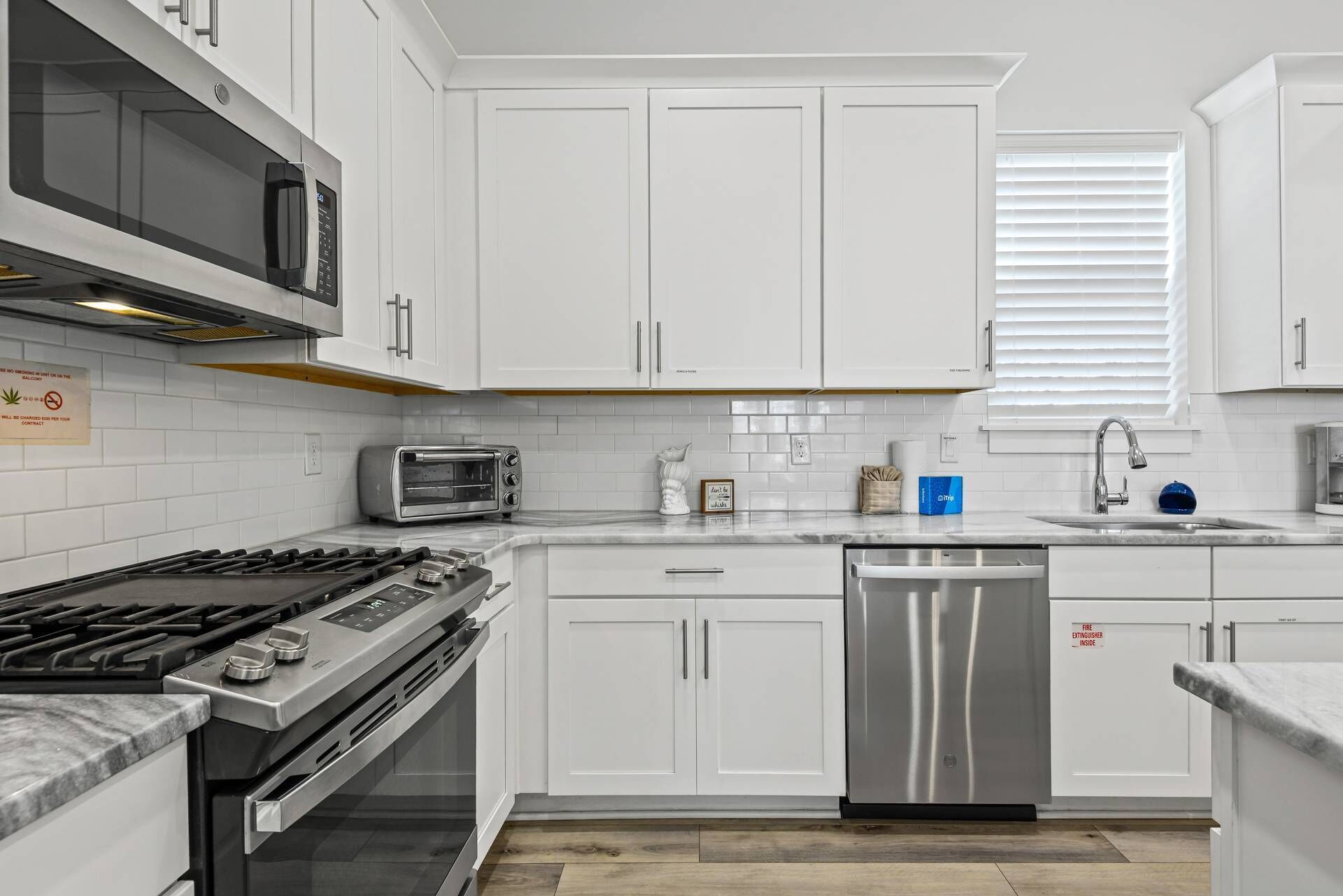 A modern kitchen with white cabinets, a stainless steel dishwasher, a gas stove, and a built-in microwave.