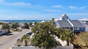 Zona residencial costeira com casas, céu azul límpido e vista para o oceano.