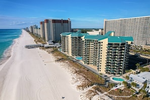 A beachfront hotel with multiple high-rise buildings, a sandy beach, and a clear blue sky. - Sunbird 204w (Panama City Beach)