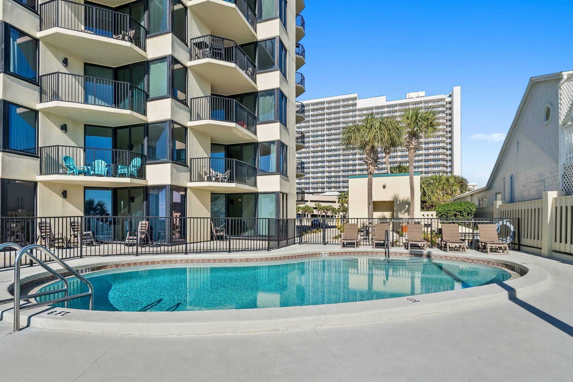 A modern hotel with a pool, outdoor seating, and a view of a tall building in the background.