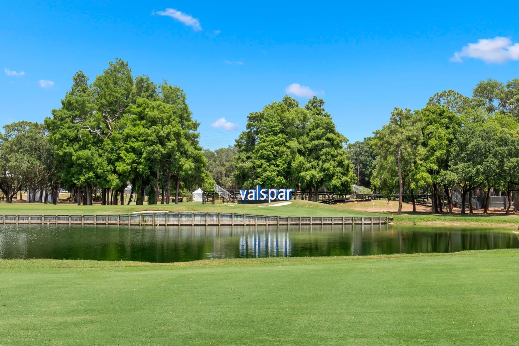 Un campo de golf con un estanque, árboles y un cartel de Valspar.