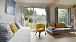 A modern living room with a sofa, armchair, and a large window. - La Maison du Bord de Mer – Charmant cocon pour 4 (Saint-Jacut-de-la-Mer)