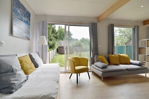 Ein modernes Wohnzimmer mit einer Couch, einem Sessel und einem großen Fenster.