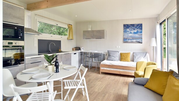 A modern kitchen with a dining area, a bed, and a sofa. - La Maison du Bord de Mer – Charmant cocon pour 4 (Saint-Jacut-de-la-Mer)