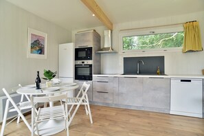 Eine moderne Küche mit Essbereich, ausgestattet mit Mikrowelle, Backofen und Geschirrspüler.