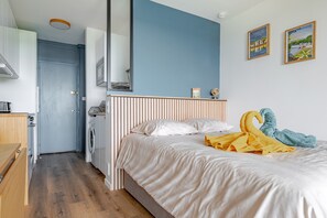 A bedroom with a bed, a wooden bench, a washing machine, and a mirror. - Bee Kaz - Beau studio à 30 min du Zoo de Beauval (Montrichard Val de Cher)