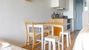 A modern kitchen with white cabinetry, a wooden dining table, and chairs. - Bee Kaz - Beau studio à 30 min du Zoo de Beauval (Montrichard Val de Cher)