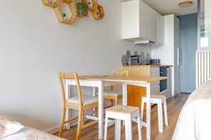A modern kitchen with white cabinetry, a wooden dining table, and chairs. - Bee Kaz - Beau studio à 30 min du Zoo de Beauval (Montrichard Val de Cher)