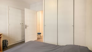 Une chambre à coucher avec un lit, une armoire et un tabouret.