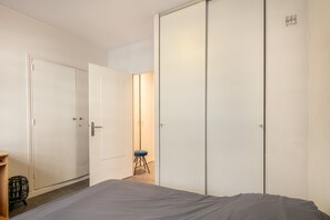 A bedroom with a bed, a wardrobe, and a stool. - Le Pradel Championnet - Bel appt centre Grenoble (Grenoble)