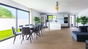 Una cocina moderna con una isla central, una zona de comedor con mesa y sillas, y una sala de estar con sofá.