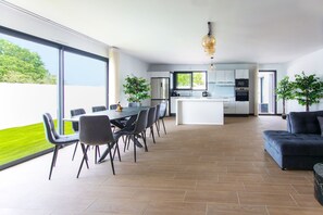 Una cocina moderna con una isla central, una zona de comedor con mesa y sillas, y una sala de estar con sofá.