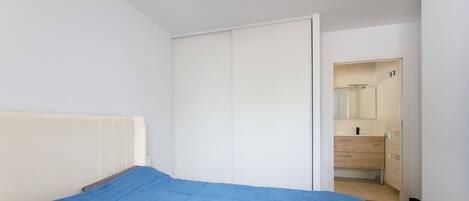 A bedroom with a bed, a wardrobe, and a bathroom visible through an open door.