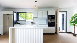 Una cocina moderna con una isla central, electrodomésticos integrados y un amplio ventanal.