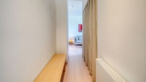 En smal hall med en träbänk, ett element och en vägg med ett mönstrat dekorativt inslag.
