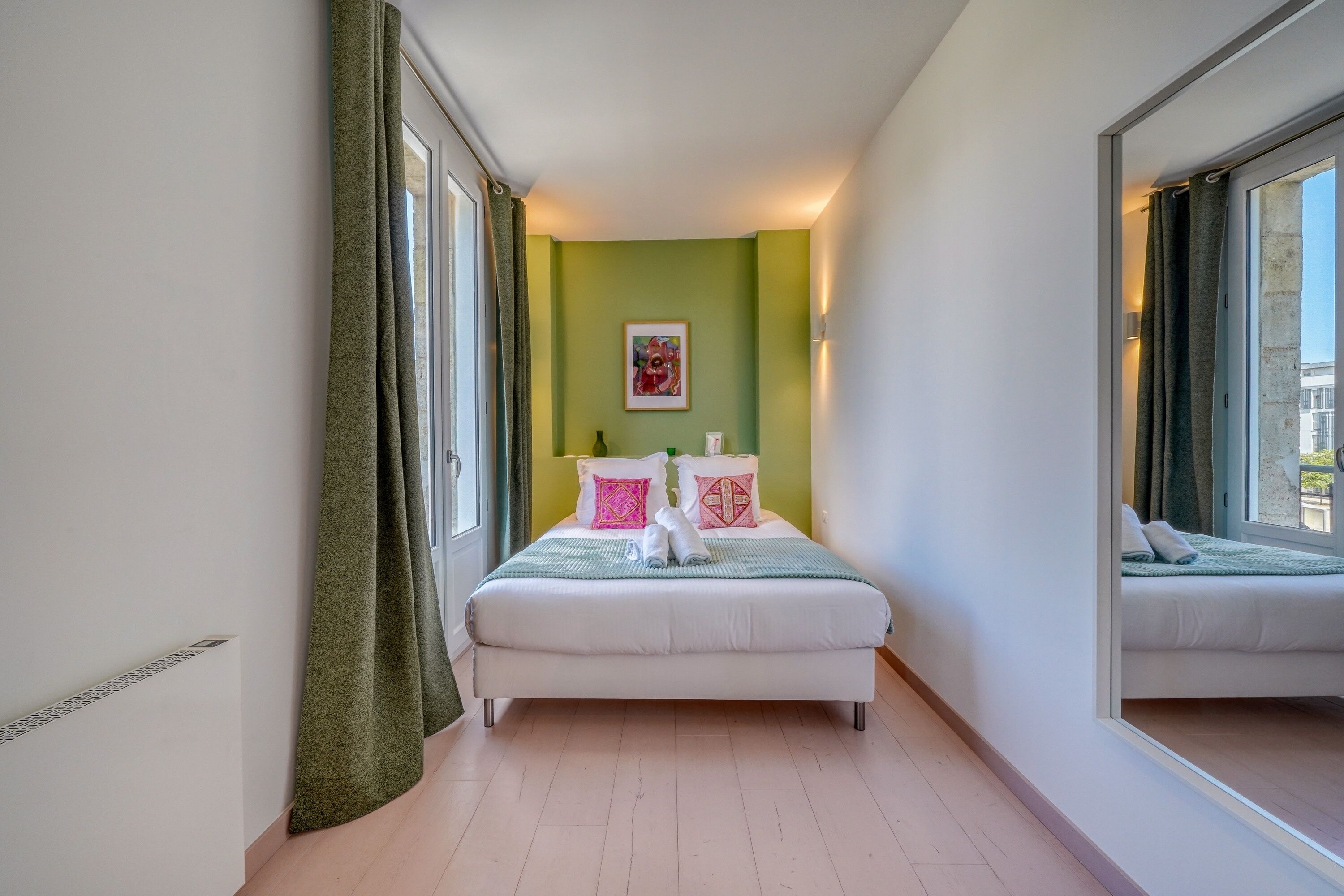 Una camera da letto con un letto, un grande specchio e una parete verde.