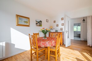 Ein Essbereich mit einem Tisch, Stühlen, einer Blumenvase und gerahmten Bildern an der Wand.