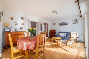 Ein Essbereich mit Tisch, Stühlen, einer Couch, Holzboden und einem Schrank.