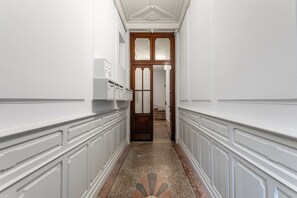 A hallway with white walls, a wooden door, and a patterned floor. - Le Cocon de Béziers - Au cœur du centre-ville (Béziers)