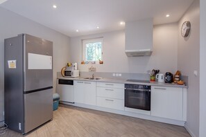 A modern kitchen with a stainless steel refrigerator, built-in microwave, oven, and dishwasher. - La Maison du Poète - Avec piscine et grand jardin (Saint-Aygulf)