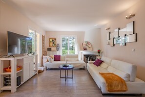 A modern living room with a flat-screen TV, white sofas, a coffee table, and a fireplace. - La Maison du Poète - Avec piscine et grand jardin (Saint-Aygulf)