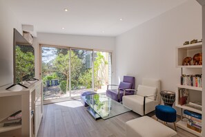 A modern living room with a glass coffee table, a white sofa, a purple armchair, and a bookshelf. - La Maison du Poète - Avec piscine et grand jardin (Saint-Aygulf)