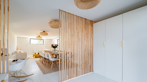 Ein modernes Interieur mit Essbereich, weißen Wänden und Holzabtrennungen.