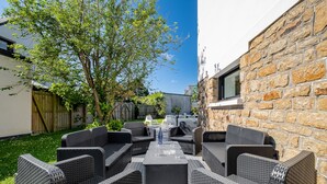Eine Terrasse im Freien mit Korbmöbeln, einer Steinmauer und einem Baum.