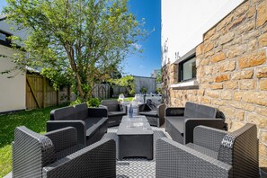 Eine Terrasse im Freien mit Korbmöbeln, einer Steinmauer und einem Baum.