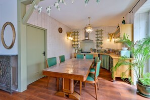 Un comedor con mesa y sillas de madera, una cocina con armarios de madera y una planta en maceta.