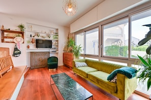 Een woonkamer met een bank, een salontafel, een televisie en een raam met uitzicht.