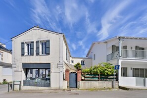 Een gebouw met twee verdiepingen, een garage, een balkon en een kleine tuin.