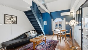 A modern living room with a staircase, a sofa, a coffee table, and a dining area. - Le Dôme - Au cœur du centre-ville de Béziers (Béziers)