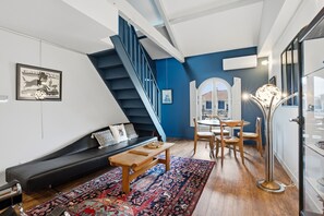 A modern living room with a staircase, a sofa, a coffee table, and a dining area. - Le Dôme - Au cœur du centre-ville de Béziers (Béziers)