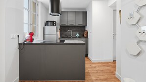 A modern kitchen with a central island, grey cabinets, and a black pendant light. - Le Dôme - Au cœur du centre-ville de Béziers (Béziers)