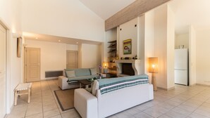 A modern living room with a sofa, a small table, a bench, a fireplace, and a refrigerator. - La Villa Amarra - À 1 km du Golf de Moliets-et-Maa (Moliets-et-Maa)